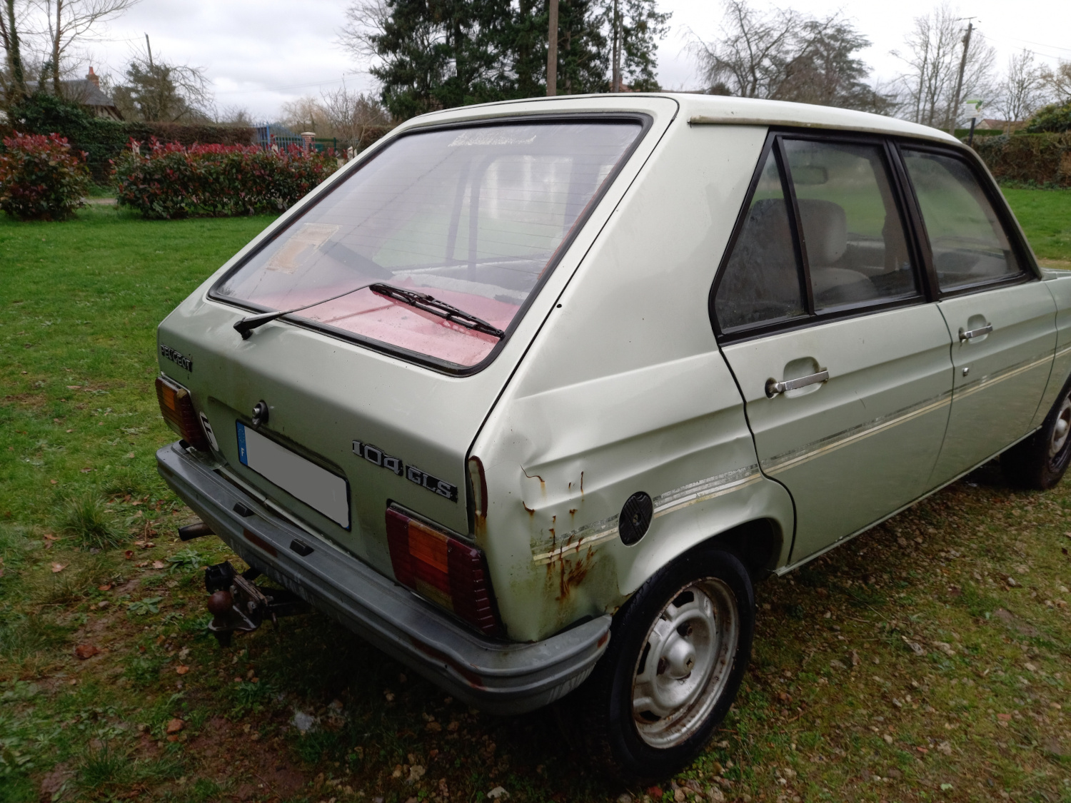Zielony Peugeot 104, lekko zdeformowana tylna 'ćwiartka' samochodu wokół wlewu paliwa